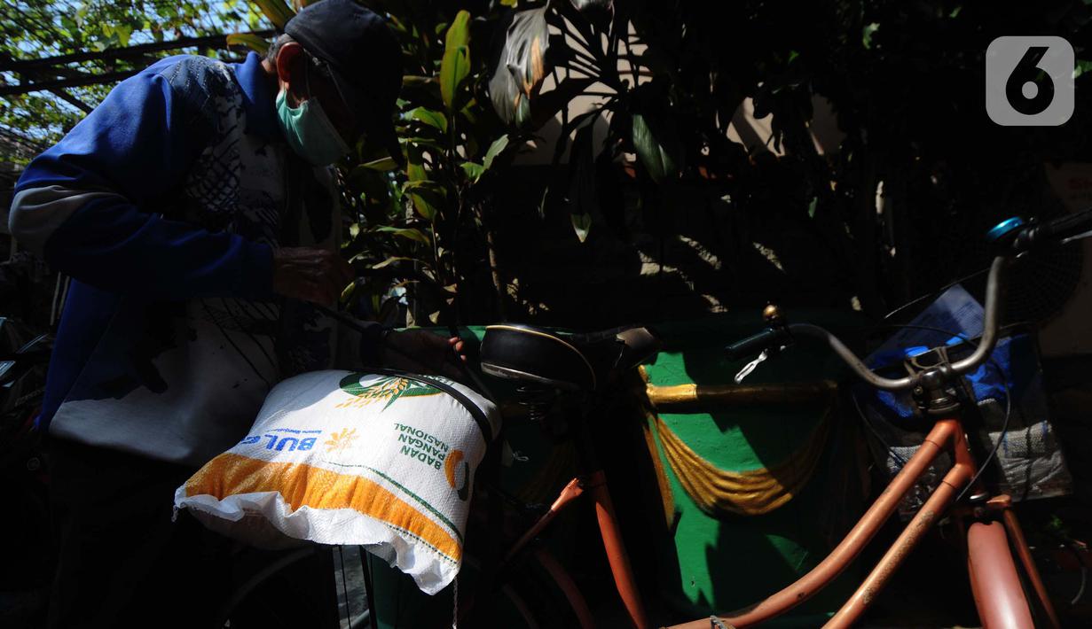 Warga menggunakan sepedanya untuk membawa beras kemasan 10 kilogram di Kelurahan Pela Mampang, Jakarta, Jumat (3/5/2024). (merdeka.com/Imam Buhori)