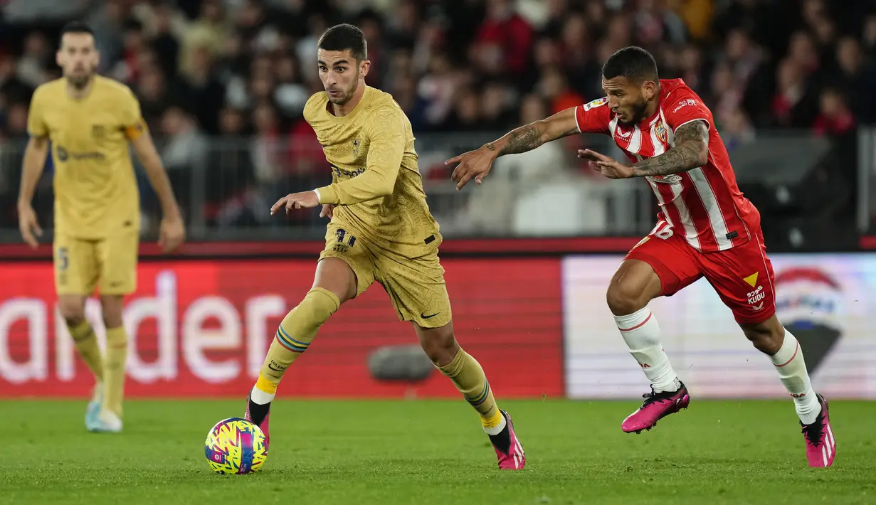 Penyerang Barcelona Ferran Torres berebut bola dengan penyerang Almeria Luis Suarez pada pekan ke-23 Liga Spanyol di Power Horse Stadium, Senin dini hari WIB (27/2/2023). Gol kemenangan Almeria dilesakkan El Bilal Toure. (AP Photo/Jose Breton)