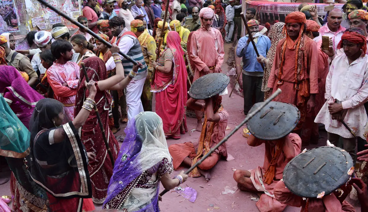 Para perempuan india memukulkan tongkat ke arah tameng yang dipegang para pria selama perayaan Lathmar Holi di Barsana, Uttar Pradesh, India (6/3). Lathmar Holi adalah festival yang dirayakan sebelumnya Holi sebenernya berlangsung. (AFP Photo/STR)