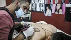 Naim Abdallah saat membuat desain tato wajah macan kumbang dengan kata-kata bahasa Inggris "the hope" di ruang kerjanya di Kota Betlehem di Tepi Barat (24/1/2021). Naim Abdallah merupakan seorang penata rambut dan seniman tato Palestina di Kota Betlehem, Tepi Barat. (AFP/Hazem Bader)