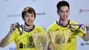 Pebulutangkis ganda putra Marcus Fernaldi Gideon dan Kevin Sanjaya Sukamuljo menunjukkan medali turnamen BWF Dubai Super Series Finals 2017, Minggu (17/12). Marcus/Kevin mempecundangi pasangan Tiongkok Zhang Nan/Liu Cheng 21-16 21-15 (GIUSEPPE CACACE/AFP)