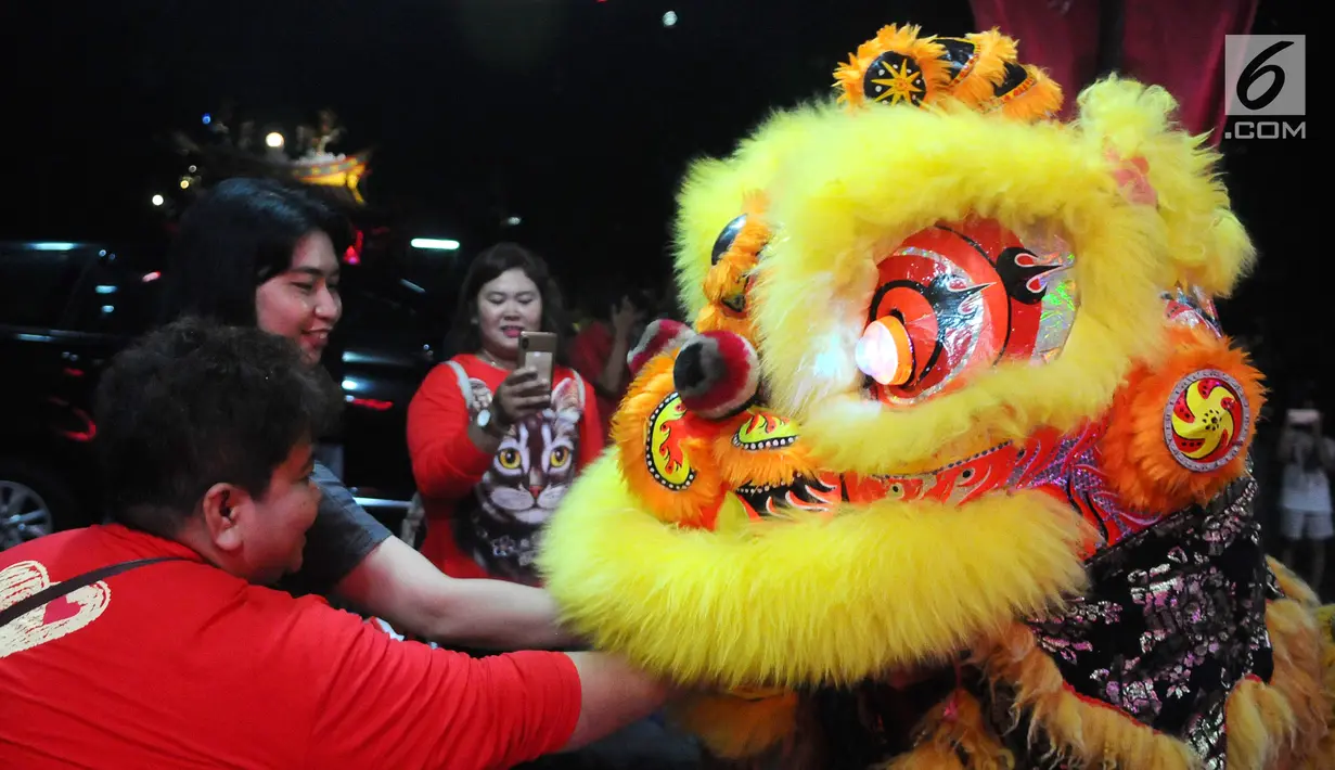 Warga keturunan Tionghoa memberikan angpao kepada penari barongsai pada malam Tahun Baru Imlek di Vihara Amurva Bhumi, Jakarta, Senin (04/2). Boneka berbentuk singa dimainkan untuk mengusir setan. (Liputan6.com/Herman Zakharia)