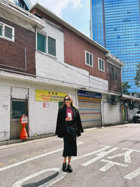Yasmine Wildblood sedang berlibur ke Korea Selatan. Gaya kerennya memadukan atasan bermotif abstrak bernuansa merah, dipadu dengan blazer hitam, dan midi skirt, serta loafers yang juga berwarna hitam. [Foto: Instagram/yaswildblood]