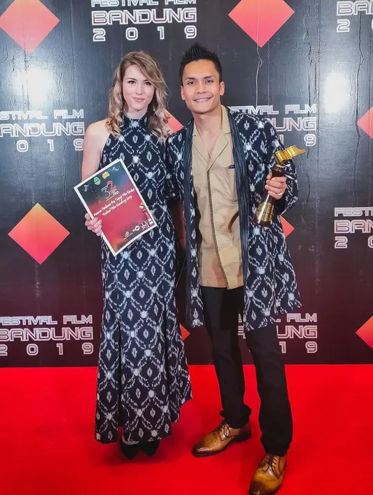 Kali ini Randy Pangalila tampil serasi dengan istri bulenya, Chelsey Franky. Keduanya tampil kompak mengenakan busana batik berwarna biru. Randy mengenakan outer batik, sementara sang istri memakai gaun batik dengan motif senada. (Liputan6.com/IG/@randpunk)