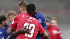 Pemain Union Berlin, Florian Huebner, berpelukan dengan pemain Schalke, Salif Sane, pada laga Bundesliga di Weserstadion Minggu (7/6/2020). Kedua tim bermain imbang 1-1. (AP/Michael Sohn)