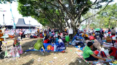 Sejumlah pengunjung beristirahat di area wisata Taman Mini Indonesia Indah, Jakarta, Minggu (19/07/2015). Makan bersama sambil menggelar tiker di tempat wisata menjadi pilihan warga yang mengunjungi tempat wisata TMII. (Liputan6.com/Yoppy Renato)