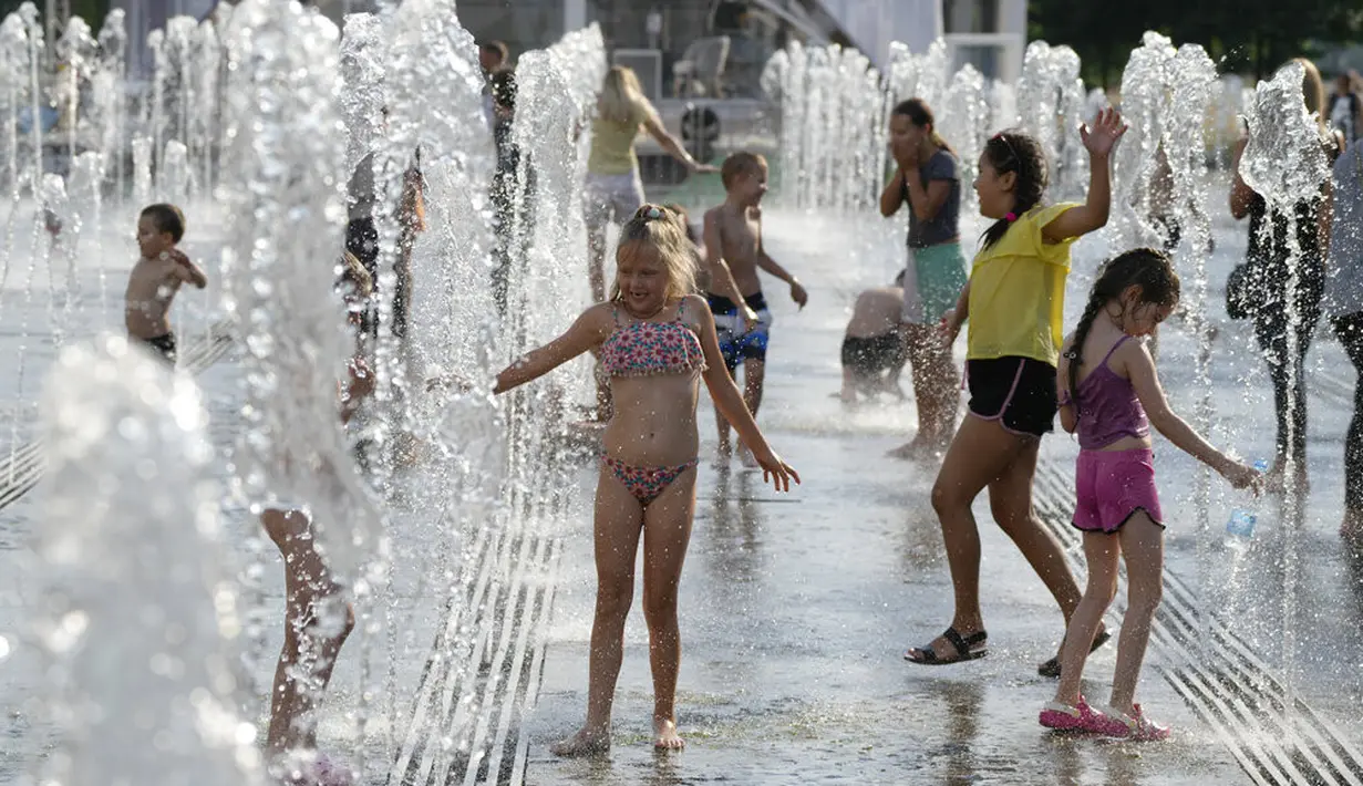 Anak-anak bermain air mancur sebuah taman di sebelah tanggul Sungai Moskow, di Moskow, Rusia, Rabu (14/7/2021). Cuaca panas di Moskow berlanjut dengan suhu mencapai 34 derajat Celcius (93,2 Fahrenheit) dalam sehari. (AP Photo/Pavel Golovkin)
