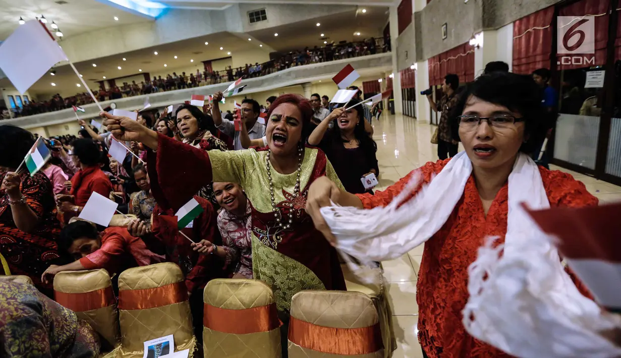 Jemaat mengibarkan bendera merah putih dan Palestina dalam acara Natal Taruna Merah Putih di Jakarta, Jumat (22/12). Perayaan natal tersebut sebagai bentuk kepedulian terhadap kedaulatan Palestina. (Liputan6.com/Faizal Fanani)