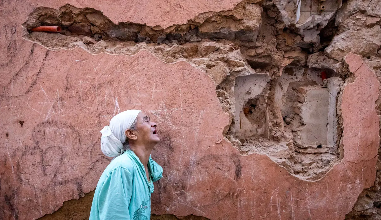 Seorang wanita bereaksi di depan rumahnya yang rusak akibat gempa bumi di kota tua Marrakesh pada 9 September 2023. Gempa kuat yang mengguncang Maroko pada 8 September menewaskan lebih dari 600 orang, menurut data kementerian dalam negeri, dan membuat warga yang ketakutan melarikan diri dari rumah mereka di tengah malam. (FADEL SENNA/AFP)