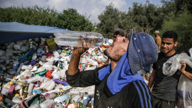 Seorang pengumpul sampah Palestina minum di tempat pembuangan sampah di Kota Gaza (29/7/2019). Kemiskinan yang terjadi akibat blokade Israel dan kurangnya kesempatan kerja membuat beberapa warga Palestina memilih bekerja mencari sampah untuk dijual. (AFP Photo/Mohammed)