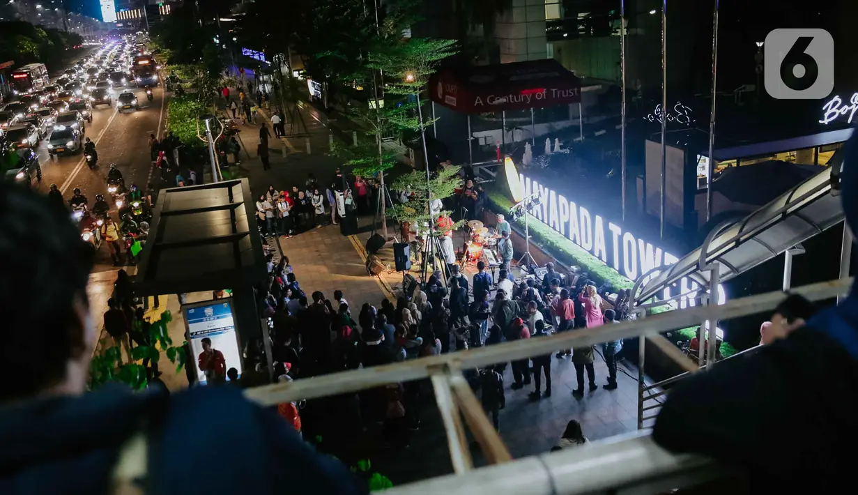 Pejalan kaki menikmati acara bertajuk Musik Tepi Barat dan Timur di jalur pedestrian kawasan Sudirman, Jakarta, Jumat (22/11/2019). Acara musik yang rutin digelar itu bertujuan untuk menghibur para pejalan kaki dan pekerja kantoran yang beraktivitas di kawasan tersebut. (Liputan6.com/Faizal Fanani)