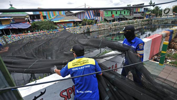 Petugas Dinas Sumber Daya Air Aliran Timur melepas kain waring atau jaring yang menutupi Kali Item di Kemayoran, Jakarta, Rabu (14/11). Pelepasan waring juga untuk mempermudah dalam membersihkan sampah di aliran Kali Item. (Merdeka.com/Iqbal S. Nugroho)