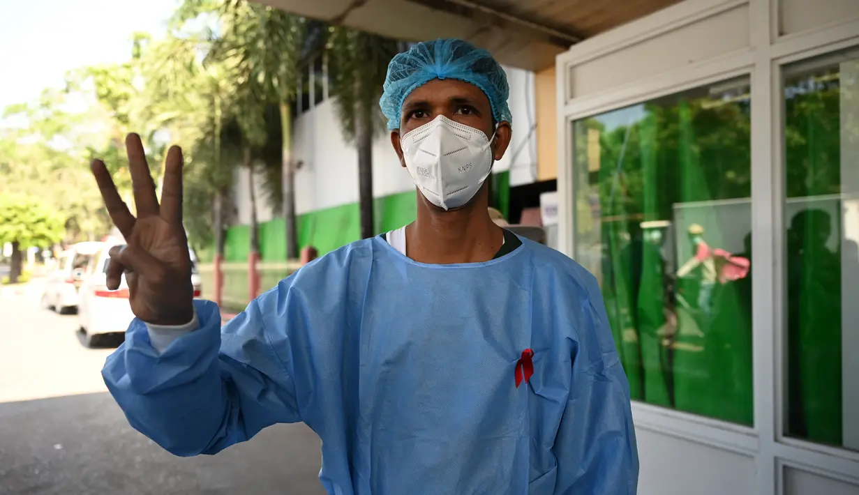 Seorang tenaga medis mengenakan pita merah di seragamnya memberi hormat tiga jari di Rumah Sakit Umum Yangon di Yangon pada 3 Februari 2021 ketika seruan untuk pembangkangan sipil semakin meningkat menyusul kudeta militer yang menahan pemimpin sipil Aung San Suu Kyi. (STR / AFP)
