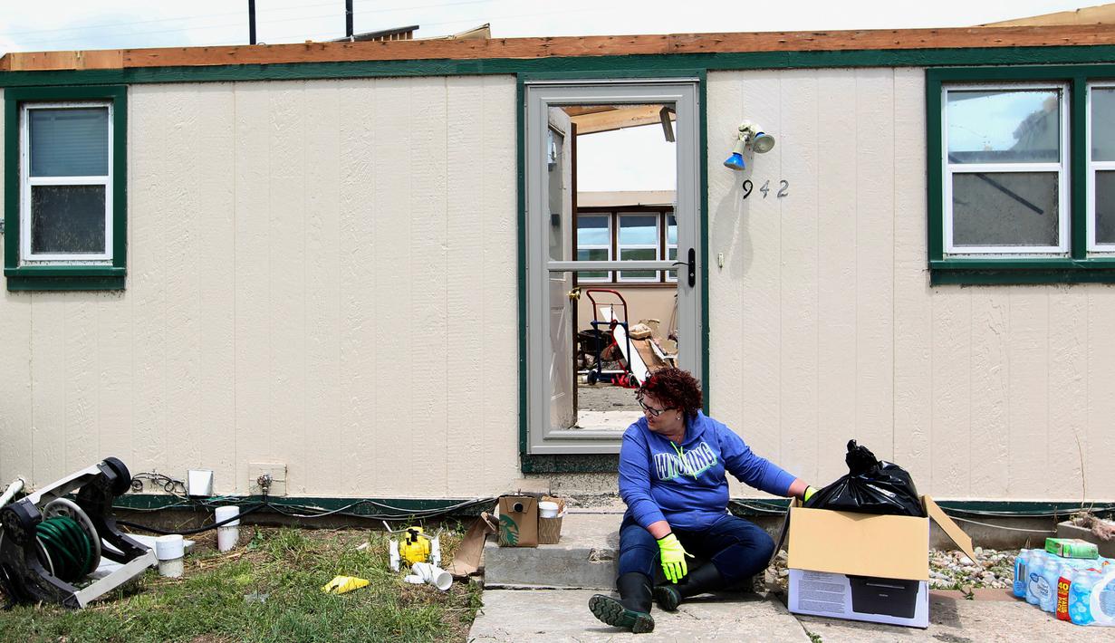 Seorang wanita duduk di depan rumahnya yang rusak usai dilanda tornado di Laramie County, Wyoming, AS (29/5). Akibat tornado ini delapan properti dan rumah rusak berat. (Jacob Byk/The Wyoming Tribune Eagle via AP)