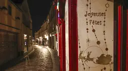 Sebuah plakat bertuliskan "Selamat Liburan" terlihat pada jalan yang kosong selama jam malam di Montmartre, Paris, Perancis, Selasa (15/12/2020). Jam malam berlaku pada pukul 20.00 hingga 06.00. (AP Photo/Michel Euler)