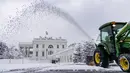 Penjaga halaman membersihkan jalan masuk di depan West Wing Gedung Putih di Washington, saat badai musim dingin bertiup ke wilayah Atlantik Tengah pada Senin (3/1/2022) dini hari. Hujan salju lebat disertai angin kencang mengguyur wilayah tenggara dan tengah Amerika Serikat. (AP Photo/Andrew Harnik)