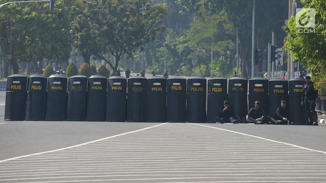 Polisi menyiapkan tameng untuk menutup jalan menuju Gedung Mahkamah Konstitusi (MK), Jakarta, Kamis (27/6/2019). Puluhan ribu personel TNI-Polri dikerahkan guna mengamankan sidang pembacaan putusan hasil sengketa pilpres 2019 serta melakukan penutupan jalan menuju Gedung MK (merdeka.com/Imam Buhori)