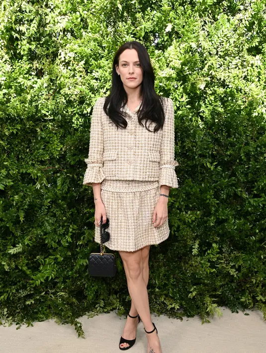 Riley  tampil memukau dalam balutan jaket tiga perempat dengan rok serasi, ditambah sepatu hak hitam; dia membawa tas tangan Chanel yang halus dan kacamata hitam. [Dok/Chanel]