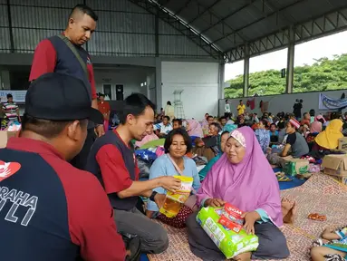 Relawan Artha Graha Peduli (AGP) memberikan bantuan kepada pengungsi imbas tsunami Selat Sunda di Rajabasa, Lampung Selatan, Kamis (27/12). Pulau Sebesi dan Sebuku menjadi  wilayah yang tertutup abu vulkanik Gunung Anak Krakatau. (Liputan6.com/HO/Rini)