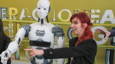 Seorang wanita berpose disamping robot InMoov rancangan Gael Langevin dalam pameran teknologi Bucharest, Romania (26/5). Robot ini dirancang berdasarkan gagasan tangan palsu buatan Langevin yang dikembangkan pada tahun 2011. (AP Photo / Vadim Ghirda)