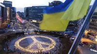 Bendera Ukraina berkibar ditiup angin saat tanda perdamaian raksasa dipasang para demonstran jelang KTT Uni Eropa dan NATO di Brussels, Belgia, 22 Maret 2022. Pengunjuk rasa meminta para pemimpin Uni Eropa memberlakukan larangan penuh terhadap bahan bakar Rusia. (AP Photo/Geert Vanden Wijngaert)