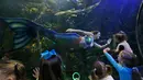 Sejumlah anak-anak menonton atraksi Malena Sharkey, wanita yang menjadi putri duyung di Virginia Aquarium di Virginia Beach (3/4). Aquarium ini menyajikan atraksi putri duyung setiap minggunya selama bulan April. (AP Photo/Steve Helber)