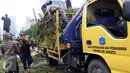 Petugas Dinas Pertamanan dan Pemakaman Provinsi DKI Jakarta mengangkut batang pohon besar yang tumbang ke atas truk  di Jakarta, Senin (1/2). Pohon tumbang yang terjadi saat hujan deras mengakibatkan kemacetan panjang. (Liputan6.com/Helmi Afandi)