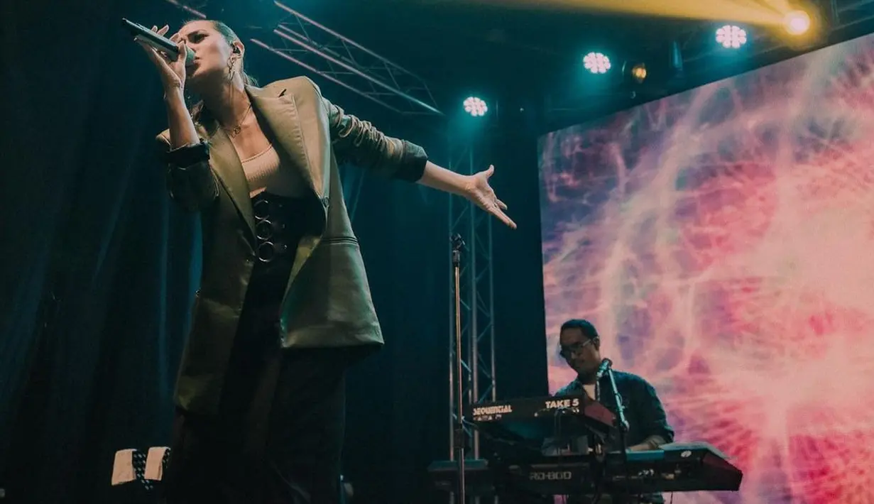 <p>Siluet oversized juga bisa menarik saat kamu mengenakan workwear. Raisa manggung mengenakan oversized leather blazer berwarna hijau, dipadunya dengan high-waisted trousers berwarna hitam. Foto: Instagram.</p>