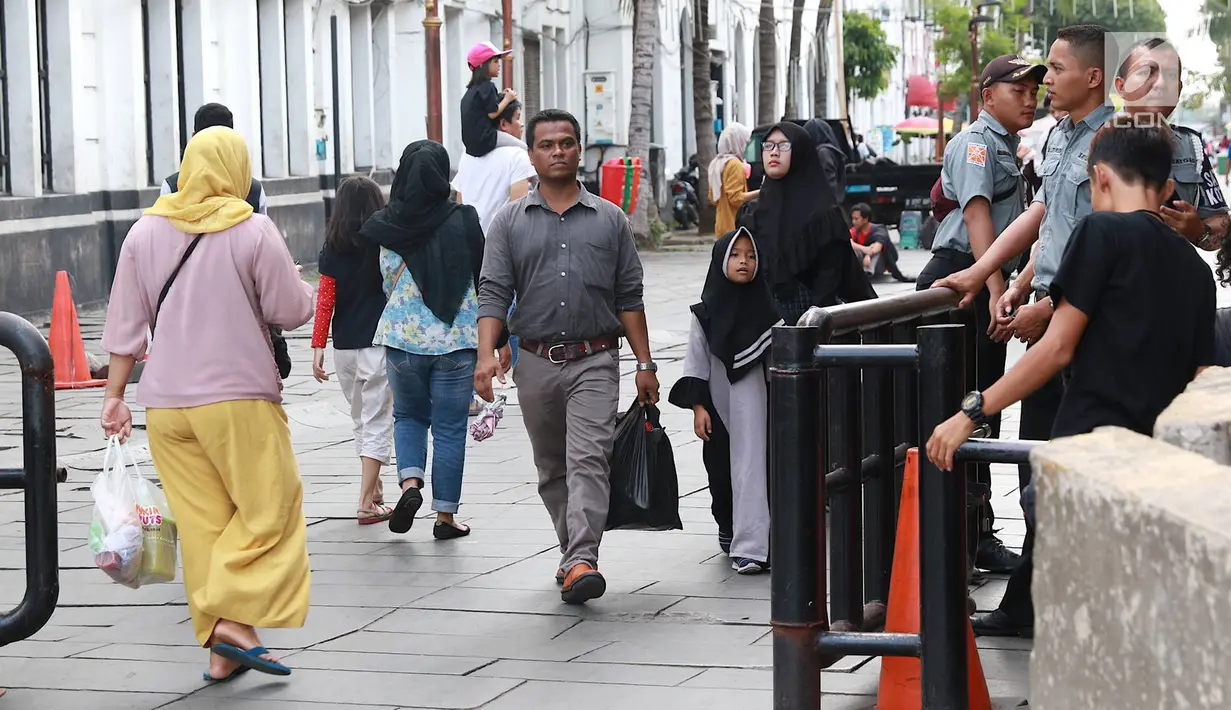 Pejalan kaki melintasi jalur masuk dan keluar Taman Fatahilah, Kota Tua, Jakarta, Selasa (23/4). Unit Pengelola Kawasan (UPK) Kota Tua melakukan uji coba simulasi pengaturan alur pintu masuk dan pintu keluar ke Taman Fatahillah bagi pejalan kaki selama dua minggu. (Liputan6.com/Immanuel Antonius)