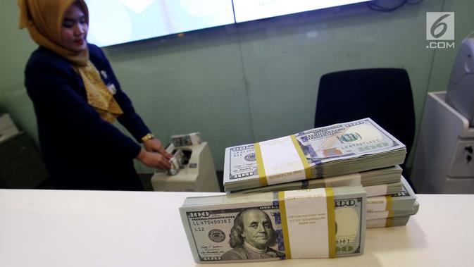 Petugas bank menghitung uang dollar AS di Jakarta, Jumat (20/10). Nilai tukar Rupiah terhadap Dolar Amerika Serikat (USD) masih belum beranjak dari level Rp 13.500-an per USD. (Liputan6.com/Angga Yuniar)
