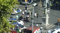 Petugas dibantu warga membantu korban setelah mobil van menabrak kerumunan orang  di Jalanan Las Ramblas, Barcelona, Spanyol (17/8). Lebih dari 50 orang dilaporkan luka-luka dan 13 orang tewas akibat kejadian tersebut. (Daniel Vil via AP)