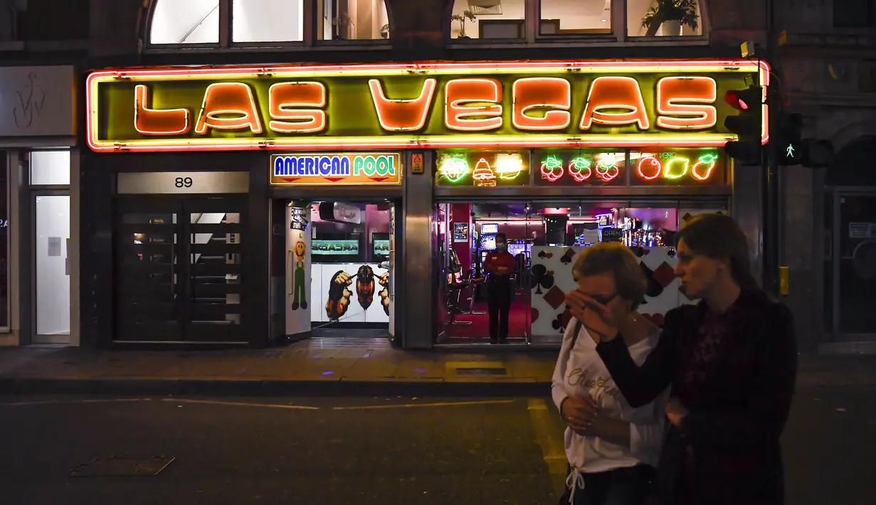 Orang-orang berjalan melewati kasino di Soho, di London, Selasa (22/9/2020). Perdana Menteri Inggris, Boris Johnson, telah mengumumkan bahwa pub dan restoran tutup pada pukul 10 malam, karena lonjakan kasus virus corona di seluruh Inggris. (AP Photo / Alberto Pezzali)