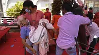 Anggota keluarga membawa pasien yang bernapas dengan bantuan oksigen yang disediakan oleh Gurdwara, tempat ibadah untuk Sikh, di bawah tenda yang dipasang di sepanjang pinggir jalan di Ghaziabad, Selasa (4/5/2021). Amukan tsunami COVID-19 di India memunculkan kelangkaan oksigen (Tauseef MUSTAFA/AFP)