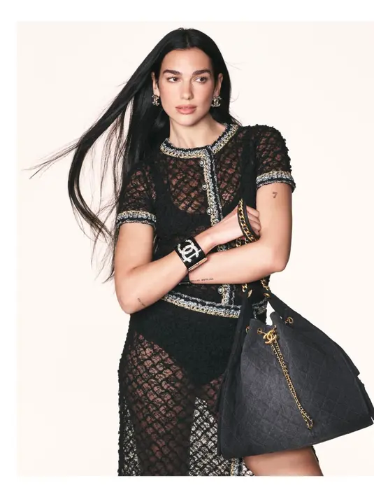 Dalam potret kedua, Dua tampil dalam gaun hitam transparan berbahan lace dengan bordiran perak yang menciptakan siluet anggun dan mewah. Tas CHANEL 25 dalam bahan quilted hitam dipadukan dengan rantai emas, melengkapi tampilan yang elegan dan sophisticated. [Dok/CHANEL].