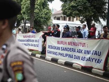 Para pengunjuk rasa membentangkan spanduk dijalan saat melakukan orasi di depan Kedutaan Besar Filipina, Jakarta, Kamis (14/7). Dalam aksinya mereka menuntut agar ABK WNI yang disandera di Filipina dibebaskan. (Liputan6.com/Faizal Fanani)