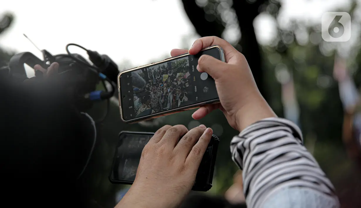 Seseorang mengambil gambar saat Gubernur DKI Jakarta Anies Baswedan menemui pendemo yang tengah melakukan orasi di depan gerbang Balai Kota DKI Jakarta, Jumat (14/10/2022). Anies melakukan diskusi dengan salah seorang perwakilan demonstran sembari disaksikan peserta unjuk rasa lain. (Liputan6.com/Faizal Fanani)