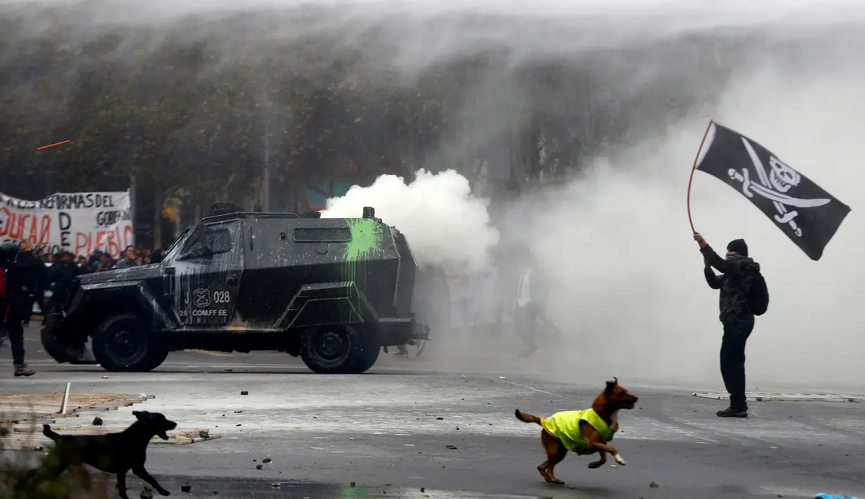 Seorang mahasiswa chili mengibarkan bendera saat bentrok dengan polisi anti huru hara menuntut perubahan sistem pendidikan di Santiago, Chili, 11 Mei 2016. (REUTERS / Ivan Alvarado)