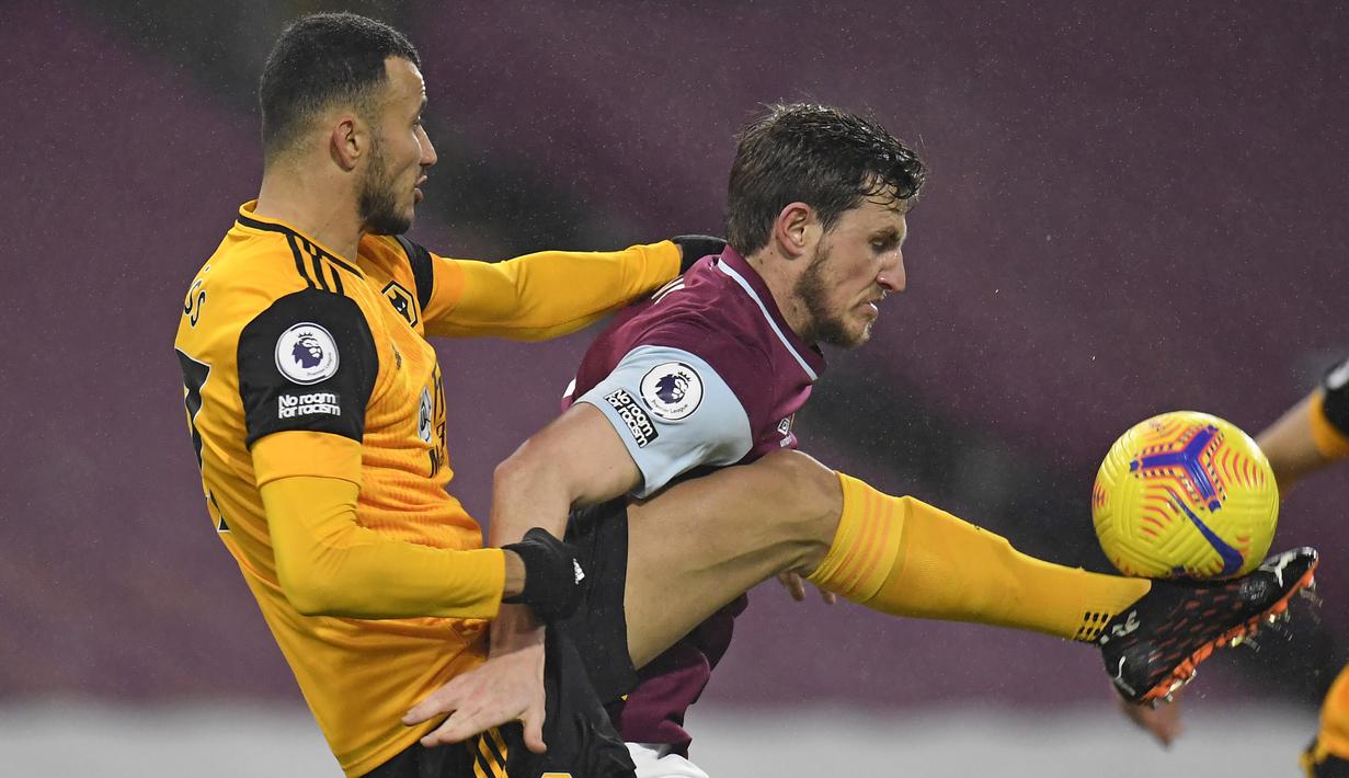 Bek Wolverhampton Wanderers, Romain Saiss (kiri), berebut bola dengan striker Burnley, Chris Wood, dalam laga lanjutan Liga Inggris pekan ke-14 di Turf Moor Stadium, Senin (21/12/2020). Wolverhampton kalah 1-2 dari Burnley. (AFP/Peter Powell/Pool)