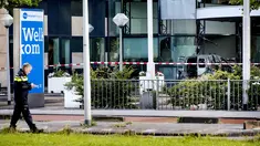 Seorang polisi berjalan dekat sebuah mobil van yang menabrak pintu depan gedung tempat surat kabar ternama Belanda, De Telegraaf di Amsterdam, Selasa (26/6). Akibatnya mobil van itu terbakar dan menyebakan kerusakan pada gedung. (KOEN VAN WEEL/ANP/AFP)