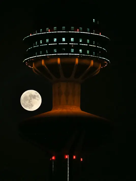 Bulan super penuh 'Buck', muncul di belakang Menara Pembebasan di Kota Kuwait, Rabu (13/7/2022). Bulan Purnama dikenal sebagai Buck Moon dan juga Supermoon. Di kondisi ini Bulan akan terlihat tampak lebih besar dan terang sehingga terasa sangat dekat dari Bumi. (YASSER AL-ZAYYAT / AFP)