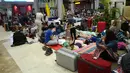 Turis asing bersantai dengan alas seadanya di lantai Bandara Internasional Lombok Praya, NTB, Senin (6/8). Imbas gempa 7 skala Richter, para wisatawan mancanegara terlantar di bandara karena jam pemberangkatan pesawat yang tertunda. (AFP/SONNY TUMBELAKA)