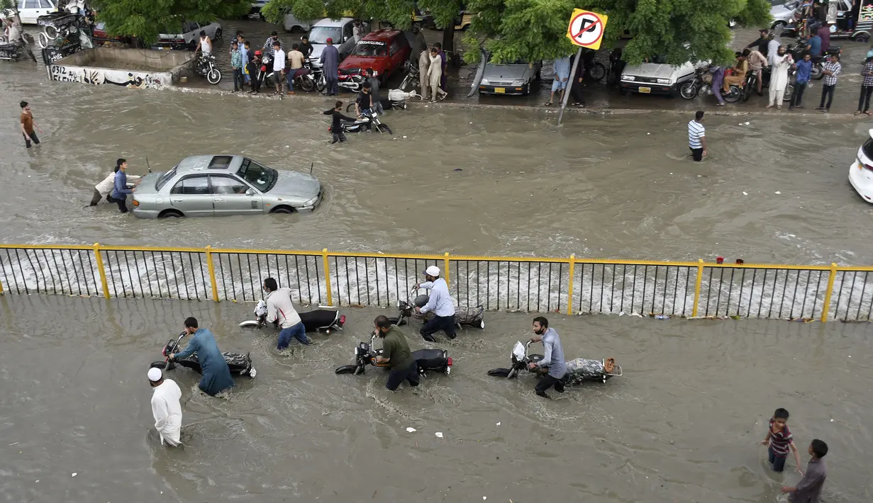 Para pengendara mendorong kendaraannya saat melewati jalan yang banjir di Karachi, Pakistan, Kamis (23/9/2021). Banjir merendam Karachi setelah diguyur hujan deras. (AP Photo/Fareed Khan)