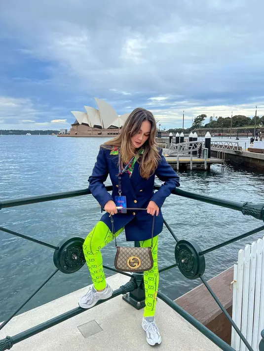 Saat berkunjung ke Australia, Luna Maya tampil modis dalam balutan brand Gucci. Ia mengenakan ocean print shirt dengan viscose jacket warna dark blue yang classy. Penampilannya itu dilengkapi dengan jacquard legging berwarna hijau neon serta shoulder bag Gucci berwarna coklat. (Instagram/lunamaya).