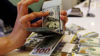 Petugas bank menghitung uang dollar AS di Jakarta, Jumat (20/10). Nilai tukar Rupiah terhadap Dolar Amerika Serikat (USD) masih belum beranjak dari level Rp 13.500-an per USD. (Liputan6.com/Angga Yuniar)