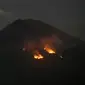 Api membakar hutan lereng Gunung Agung setelah terjadinya lontaran batu pijar dari kawah terlihat dari Karangasem, Bali, Selasa (3/7). PVMBG mencatat terjadinya erupsi Gunung Agung secara strombolian dan terdengar pula suara dentuman (AP/Firdia Lisnawati)