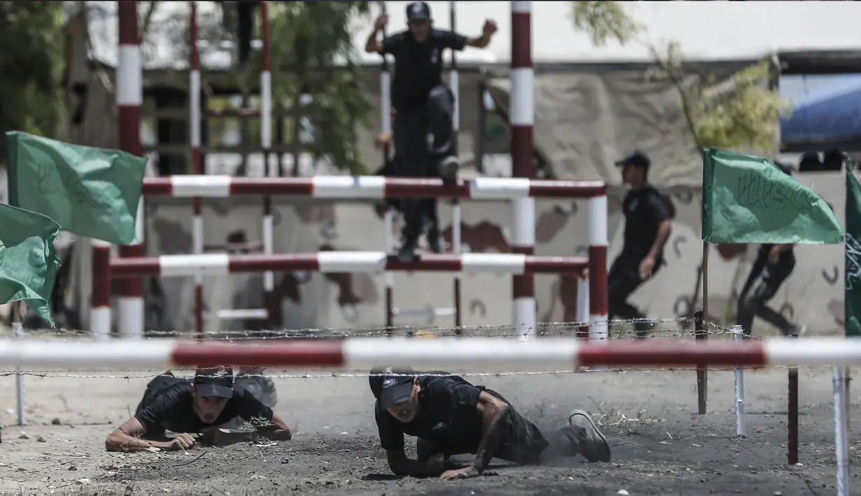 Dua kadet Palestina melewati rintangan kawat berduri saat berlatih fisik dengan militer Hamas, Brigade Ezzedin al-Qassam, di Kota Gaza (20/7/2019). Sejumlah pemuda Palestina direkrut Hamas untuk menjadi bagian anggotanya. (AFP Photo/Mahmud Hams)