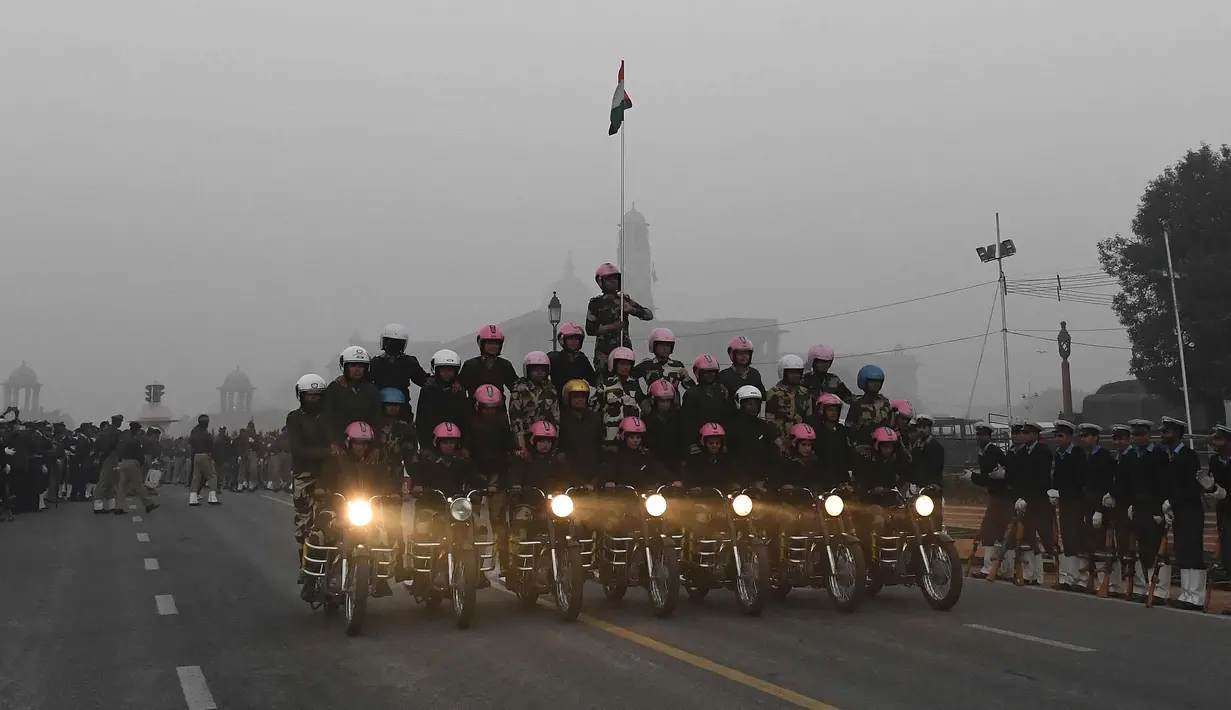 Aksi prajurit wanita dari Pasukan Keamanan Perbatasan India (BSF) beraksi di atas motor sambil membawa bendera India selama latihan untuk Parade Hari Republik di New Delhi, India, Rabu (10/1). (AFP Photo/Prakash Singh)