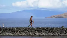Vicente Ruboi berjalan setelah kebakaran hutan yang melanda Maui di sepanjang tembok laut, di Kihei, Hawaii,  Selasa, 15 Agustus 2023. (AP Photo/Rick Bowmer)
