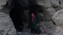 Seorang gadis kecil berdiri di pintu masuk gua di kota Bamiyan, Kabul. Foto diambil pada 19 Juni 2015. Ratusan warga miskin Afghanistan terpaksa menghuni gua-gua tersebut untuk dijadikan rumah karena tak memiliki tempat tinggal. (AFP PHOTO / SHAH Marai)