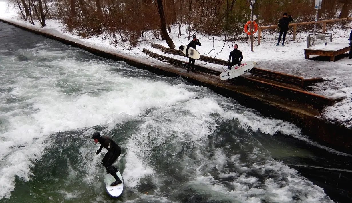 Seorang pria menaklukkan ombak saat berselancar di Sungai Eisbach selama hari musim dingin di Munich, Jerman, 4 Januari 2017. Sungai ini dipakai sebagai tempat berselancar sejak 1972 namun baru secara resmi diperbolehkan pada 2010. (Mark RALSTON/AFP)